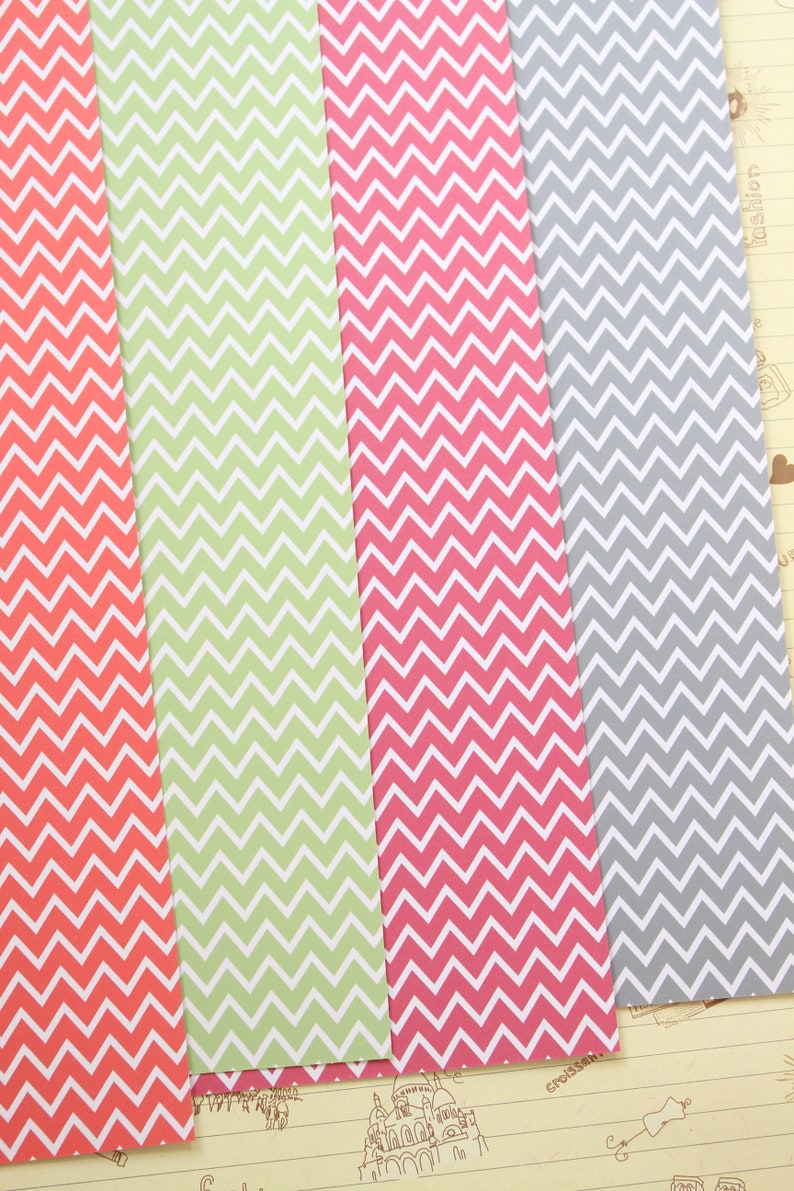 Pode incluir: Tr&ecirc;s folhas de papel com um padr&atilde;o chevron. O papel &eacute; em tons de coral, verde e cinza.