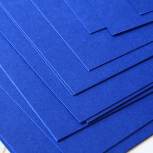 May include: Stack of blue cardstock paper. The paper has a textured surface.