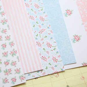 May include: A set of six patterned paper sheets in pink and blue with floral and stripe designs.
