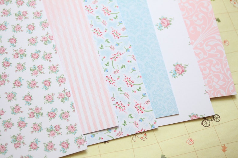 May include: A set of six patterned paper sheets in pink and blue with floral and stripe designs.
