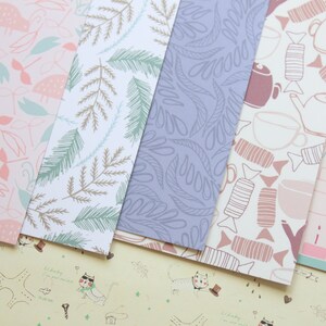May include: Five different patterned sheets of paper. The patterns include pink and green mushrooms, brown and green leaves, blue leaves, pink and brown candy, and pink and blue balloons and cups.