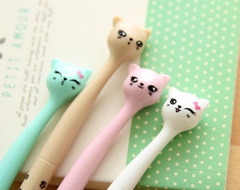 May include: Four cat-shaped pens in different colors: light blue, beige, pink, and white. Each pen has a cute cartoon cat face with black eyes and a pink nose.
