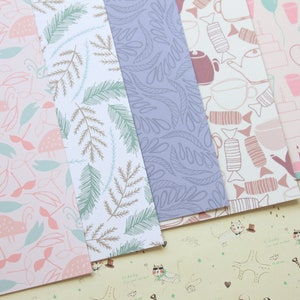May include: Five different patterned sheets of wrapping paper. The patterns include pink and green leaves, brown and green branches, purple leaves, brown and pink candy, and pink and white cups and balloons.