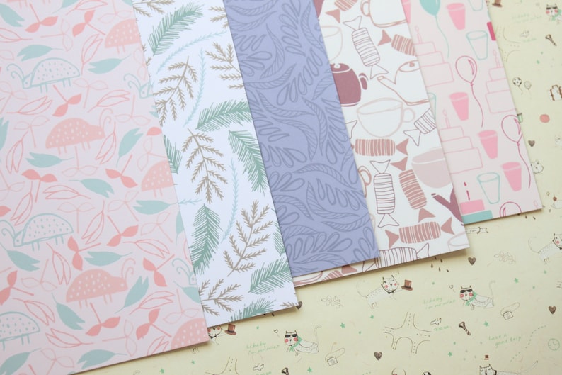 May include: Five different patterned sheets of wrapping paper. The patterns include pink and green leaves, brown and green branches, purple leaves, brown and pink candy, and pink and white cups and balloons.