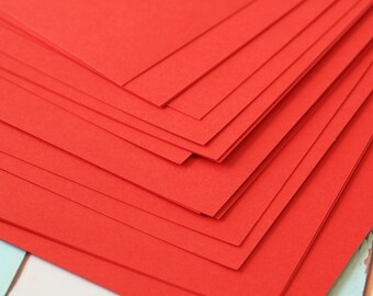 May include: A stack of red construction paper. The paper is folded in a way that creates a diagonal pattern.