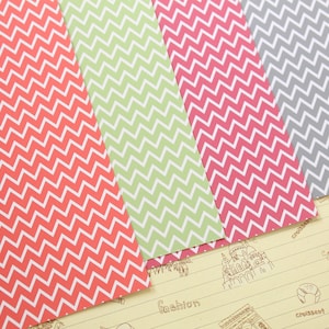Pode incluir: Quatro folhas de papel estampado com um design de chevron. O papel &eacute; em tons de vermelho, verde, rosa e cinza.