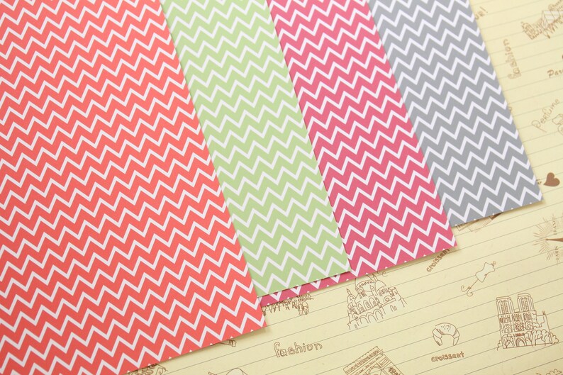 Pode incluir: Quatro folhas de papel estampado com um design de chevron. O papel &eacute; em tons de vermelho, verde, rosa e cinza.