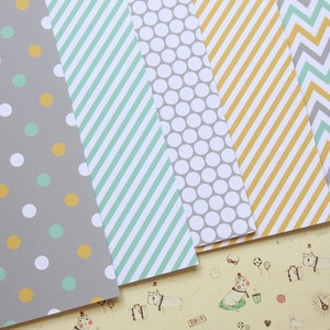 May include: Five sheets of patterned paper in various designs. The patterns include polka dots, stripes, and chevron. The colors are gray, white, yellow, and green.