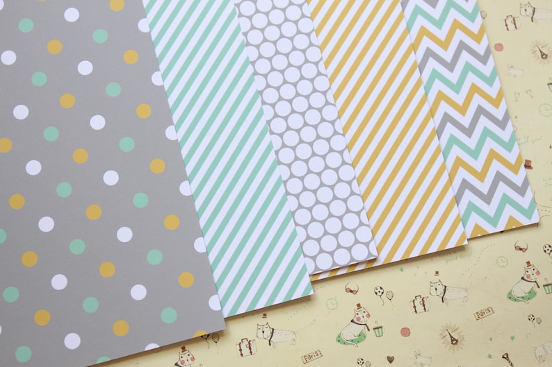 May include: Five sheets of patterned paper in various designs. The patterns include polka dots, stripes, and chevron. The colors are gray, white, yellow, and green.