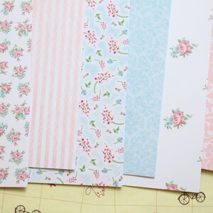 May include: A set of six patterned paper sheets in pink, blue, and white. The patterns include floral designs, stripes, and swirls.