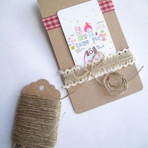 May include: A brown card with a white card attached to it. The white card has a drawing of two cartoon characters with the text "take pic" and other text. The card is tied with a brown twine and a white lace ribbon. A brown tag with twine is in the lower left corner of the image.