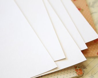 May include: Stack of blank white paper sheets on top of a patterned notebook.