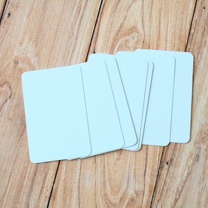 May include: A stack of blank white index cards on a wooden surface.