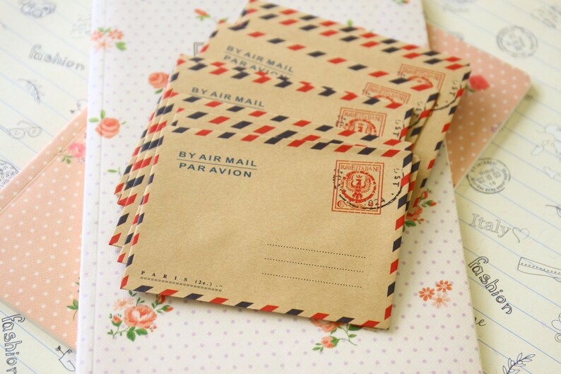 May include: A stack of brown envelopes with red and blue stripes and the text "BY AIR MAIL PAR AVION". The envelopes have a red and blue stamp with a design of a crown and the text "POSTE ITALIANE".