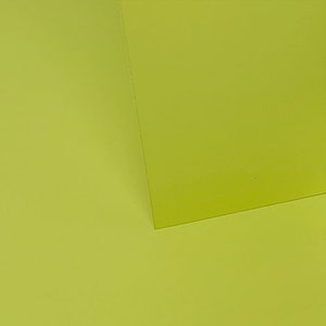 May include: Two pieces of paper, one on top of the other. The top piece of paper is a bright yellow-green color. The bottom piece of paper is a slightly darker shade of yellow-green.