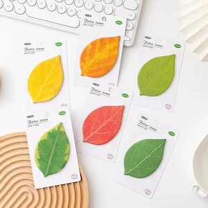 May include: Five individual packs of leaf-shaped sticky notes, each labeled Fallen leaves post-it note. The designs include a solid yellow leaf, an orange-yellow gradient leaf, a light green leaf, a variegated green leaf, and a red leaf.
