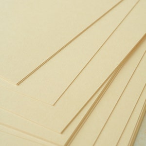 May include: A stack of cream-colored paper sheets, arranged in a fan shape, with the top sheet folded over the others.