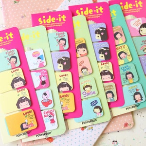 May include: A set of four pink, yellow, green, and purple sticky note pads with colorful cartoon illustrations and text. Each pad has 10 adhesive notes with different designs. The text on the notes includes "Fight for your right", "Look!", "I'm not happy", "Christmas", "Missing you", "Hey!!", "Team Do it!", "Always Smile", "I can do it", "Look!" and "I love you".