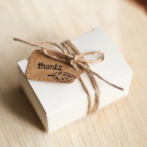 May include: A white gift box tied with twine and a brown paper tag that says "thanks" with a leaf design.