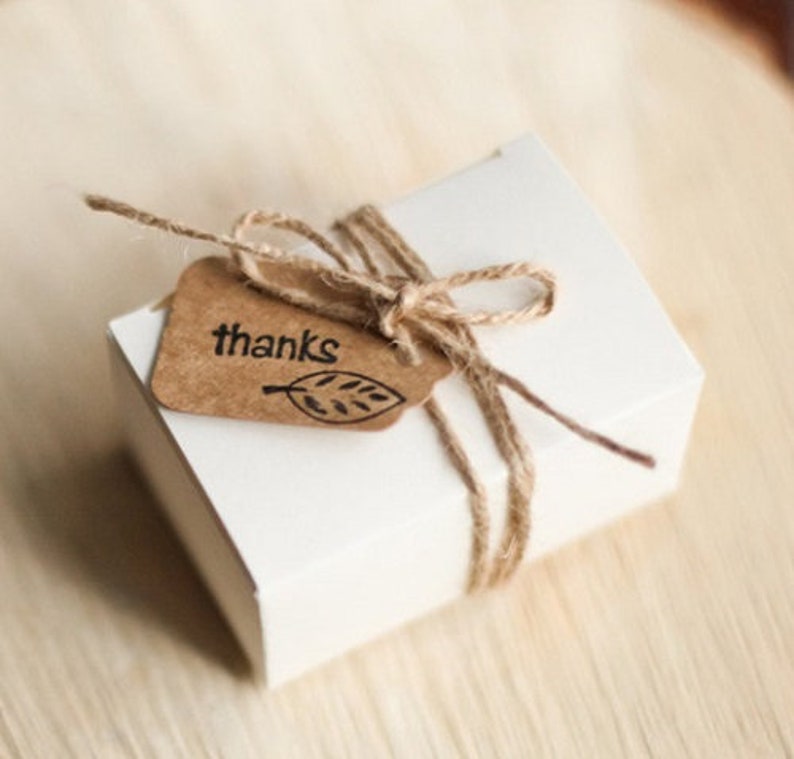May include: A white gift box tied with twine and a brown paper tag that says "thanks" with a leaf design.