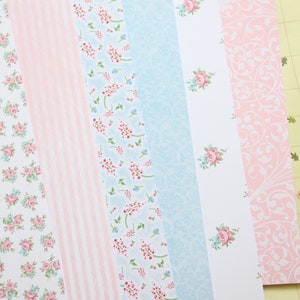 May include: A set of six patterned paper strips in pink and blue with floral and stripe designs. The paper is perfect for scrapbooking, card making, and other craft projects.