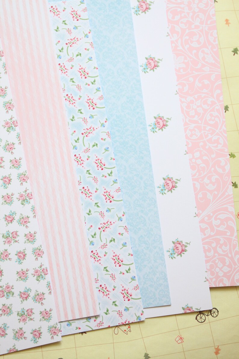 May include: A set of six patterned paper strips in pink and blue with floral and stripe designs. The paper is perfect for scrapbooking, card making, and other craft projects.