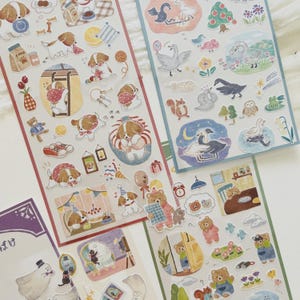 May include: A collection of decorative stickers featuring whimsical illustrations. The stickers depict various scenes, including dogs, swans, bears, and other cute animals. The color palette includes soft pastels and playful designs, perfect for scrapbooking or crafts.