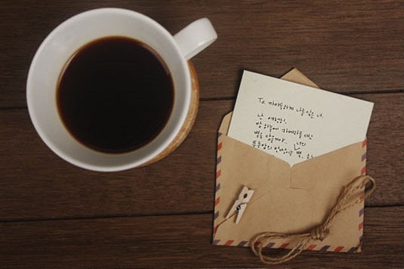 May include: A brown envelope with a handwritten note inside. The note says "To my love, I love you so much. I miss you. I wish you were here. We can overcome..." The envelope is tied with twine and has a small wooden peg attached.
