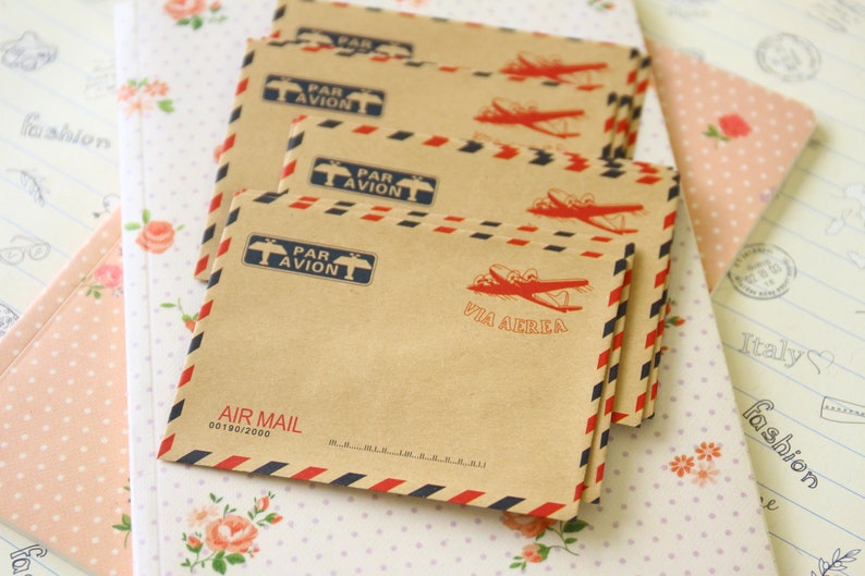 May include: A stack of brown airmail envelopes with red and blue stripes. The envelopes feature a vintage airplane design and the text "Par Avion" and "Via Aerea".