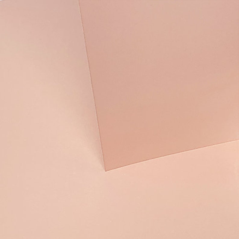 May include: A close-up of two pieces of pale pink paper, one on top of the other, creating a subtle shadow effect.