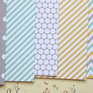 May include: Five sheets of patterned paper with different designs. The designs include gray and yellow polka dots, green and white stripes, gray and white polka dots, yellow and white stripes, and gray and green chevron.
