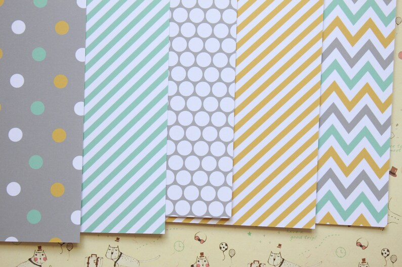 May include: Five sheets of patterned paper with different designs. The designs include gray and yellow polka dots, green and white stripes, gray and white polka dots, yellow and white stripes, and gray and green chevron.