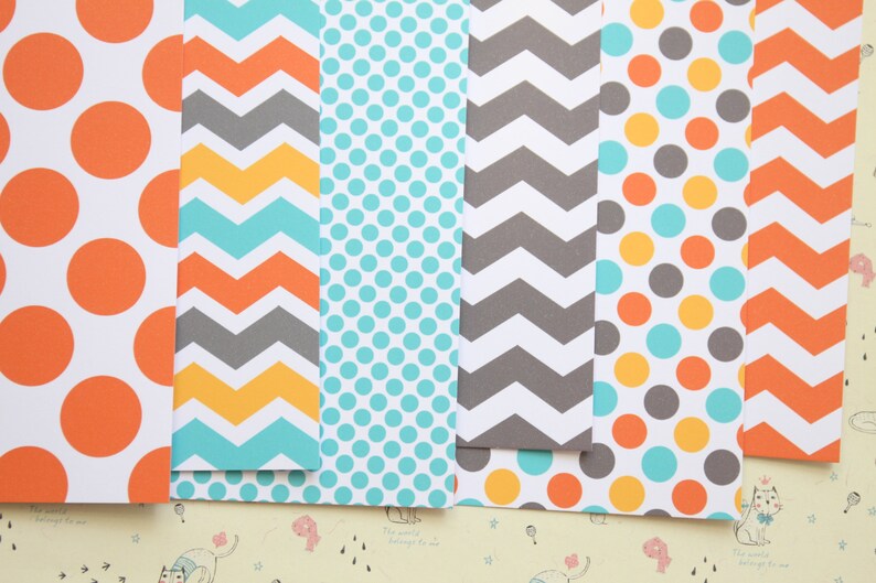 May include: Six sheets of patterned paper with different designs. The designs include orange polka dots, gray and yellow chevron, teal polka dots, gray chevron, orange, teal, and yellow polka dots, and orange chevron.