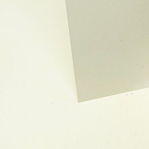 May include: Two pieces of paper, one white and one light gray, are placed on top of each other. The white paper is on the bottom and the gray paper is on top. The gray paper is slightly angled, creating a diagonal line across the image.