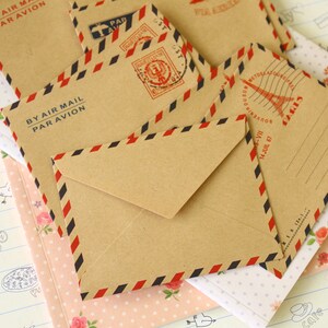May include: A set of six brown paper envelopes with red, white and blue stripes. The envelopes have the text "By Air Mail Par Avion" printed on them.