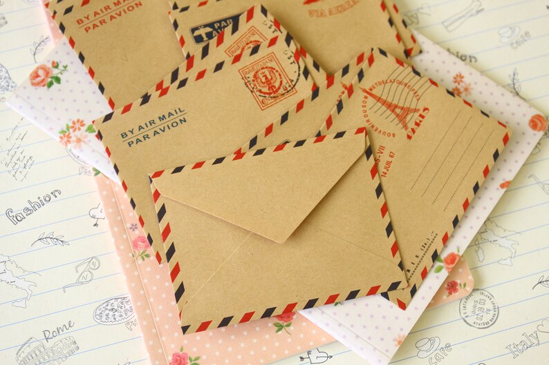 May include: A set of six brown paper envelopes with red, white and blue stripes. The envelopes have the text "By Air Mail Par Avion" printed on them.