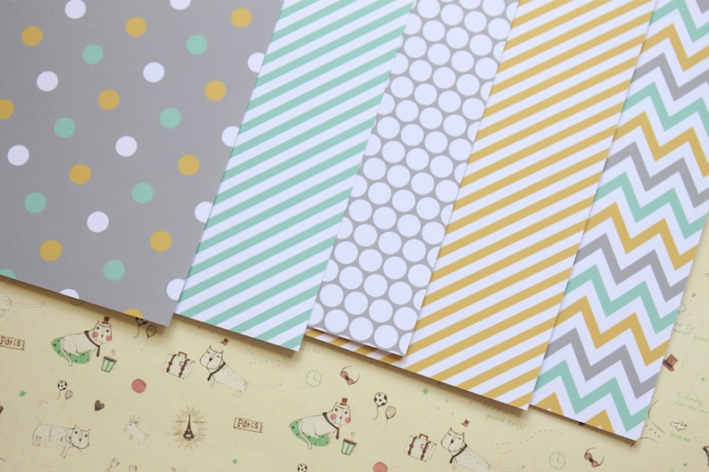 May include: Five sheets of patterned paper with different designs. The patterns include polka dots, stripes, and chevron. The colors are gray, yellow, and light blue.