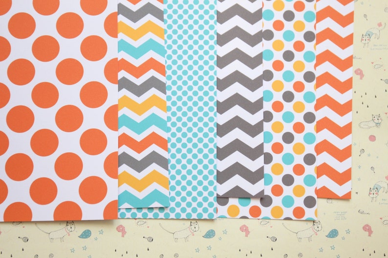 May include: A set of six patterned scrapbook papers. The papers feature a variety of patterns, including polka dots, chevron, and stripes. The colors are orange, yellow, blue, and gray.