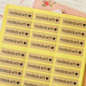 Papier kraft fait main avec des étiquettes autocollantes de pâtisserie artisanales imprimées en forme de coeur d'amour
