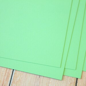 May include: Four sheets of bright green cardstock paper stacked on top of each other.