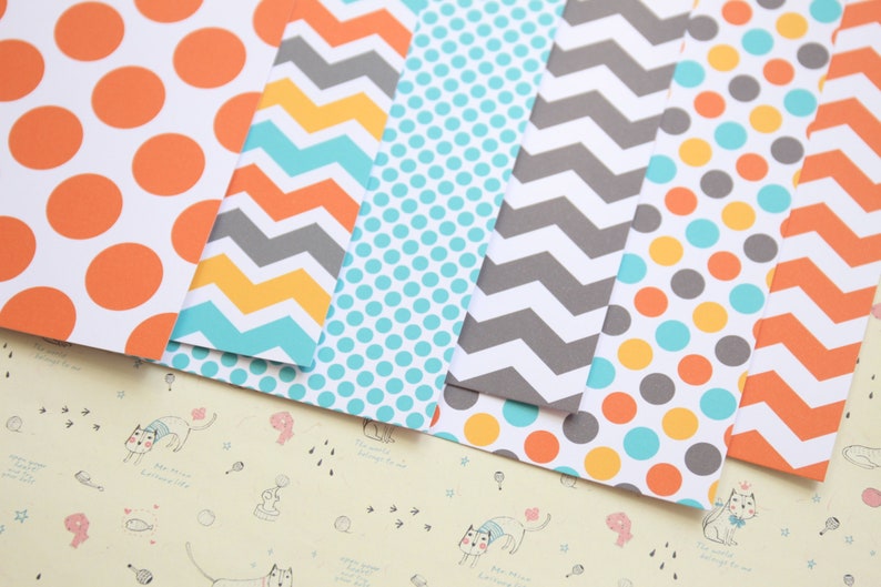 May include: A set of six patterned scrapbook papers featuring orange, yellow, gray, and blue colors. The patterns include polka dots, chevron, and stripes.