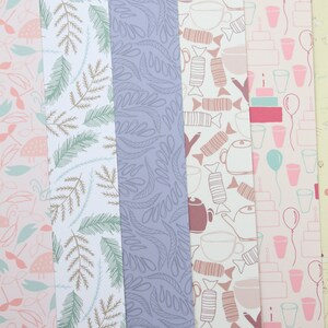 May include: Five different patterned sheets of wrapping paper. The patterns include a light blue and brown leaf design, a purple leaf design, a brown and white teacup and candy design, a pink and white cake and balloon design, and a pink and white bird design.