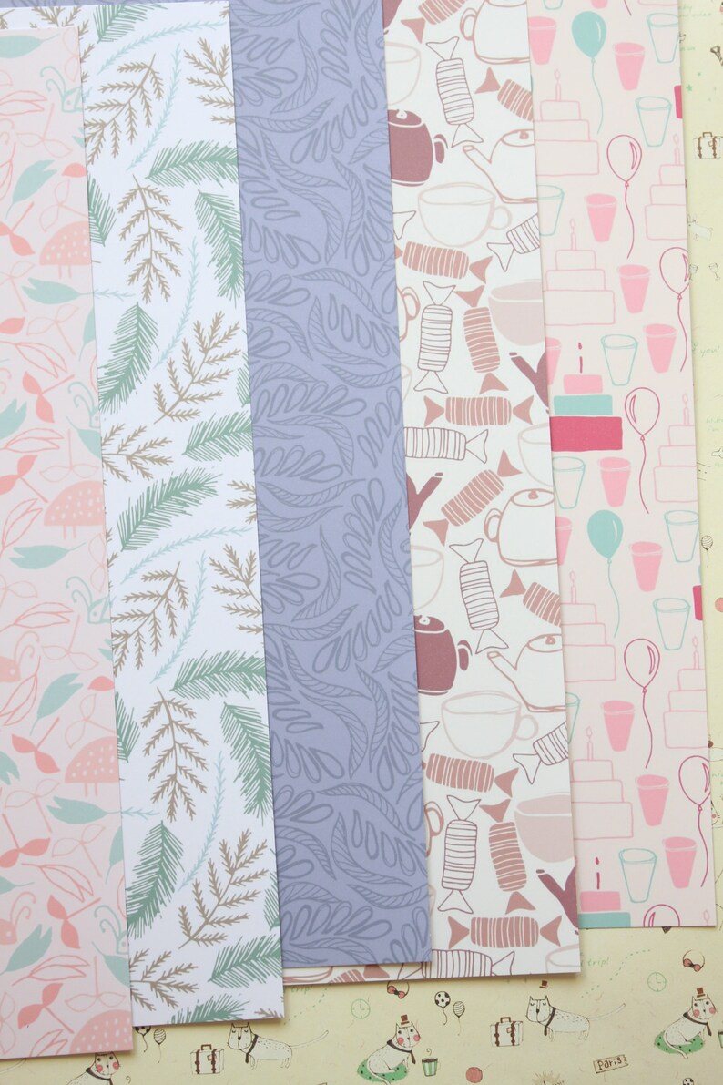 May include: Five different patterned sheets of wrapping paper. The patterns include a light blue and brown leaf design, a purple leaf design, a brown and white teacup and candy design, a pink and white cake and balloon design, and a pink and white bird design.