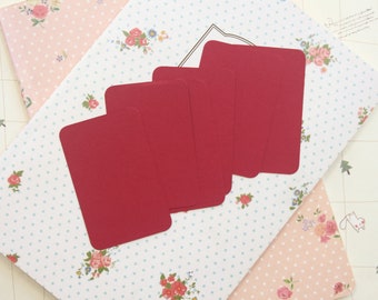 May include: Six blank red cards on a white background with a floral pattern. The cards are arranged in a staggered pattern.
