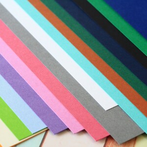 May include: A collection of 15 different colored cardstock paper sheets arranged in a fan shape. The colors include orange, yellow, green, light blue, purple, pink, red, gray, white, turquoise, brown, dark green, navy blue, black, and dark blue.
