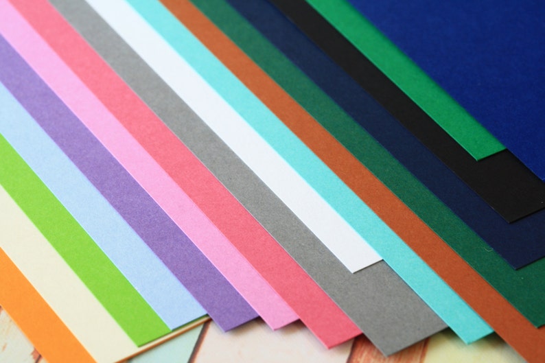 May include: A collection of 15 different colored cardstock paper sheets arranged in a fan shape. The colors include orange, yellow, green, light blue, purple, pink, red, gray, white, turquoise, brown, dark green, navy blue, black, and dark blue.
