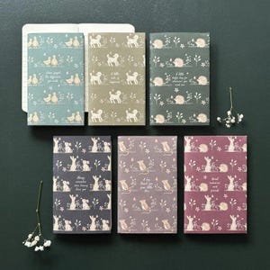 May include: Six notebooks with animal and floral designs. The notebooks feature ducks, dogs, hedgehogs, rabbits, and mice. Each notebook has a different colour scheme, including teal, olive green, and purple. Some notebooks have text.