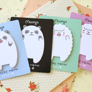 May include: Four colorful sticky note pads with different animal designs. Each pad has a white background with a black outline of a panda, sheep, or sheep. The pads are labeled "Moongs Sticky Memo" and "Moongs Cky Memo".