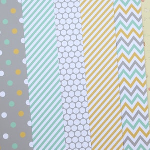May include: Five different patterned paper sheets. The sheets are gray, white, and yellow with green, gray, and yellow patterns. The patterns include polka dots, stripes, and chevron.