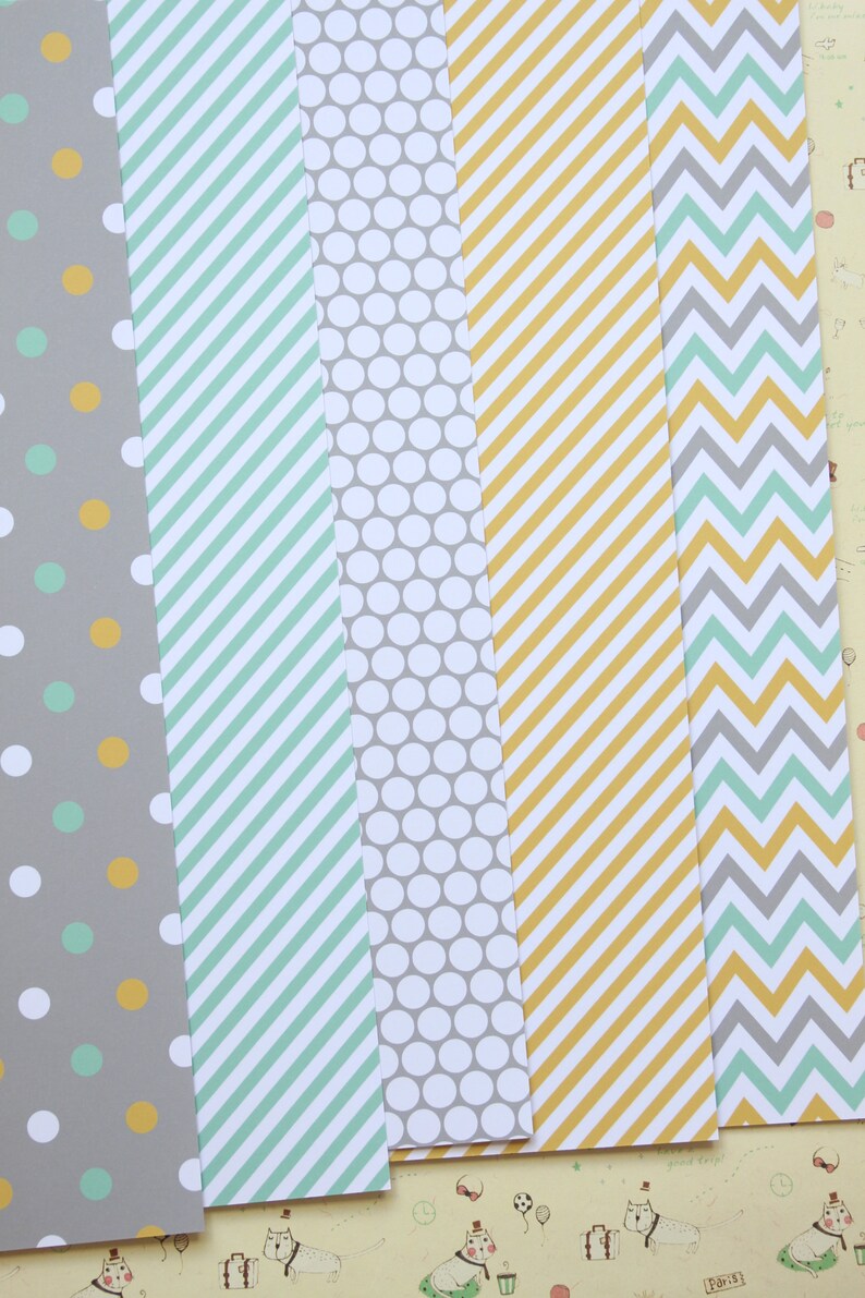 May include: Five different patterned paper sheets. The sheets are gray, white, and yellow with green, gray, and yellow patterns. The patterns include polka dots, stripes, and chevron.